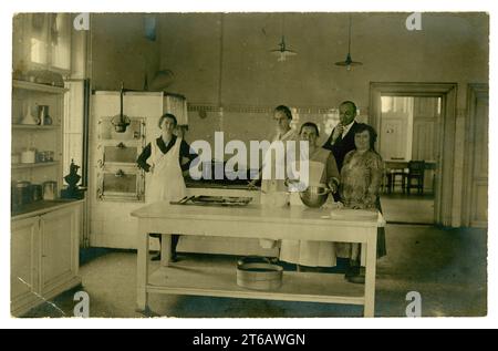 Ursprüngliche Postkarte aus den 1920er Jahren mit Köchen in einer großen Küche, Kellner, Managerin in einem Kleid mit tiefer Taille, kleines Hotel oder Institution, um 1925. GROSSBRITANNIEN Stockfoto