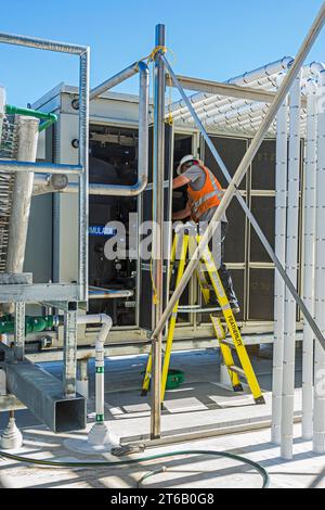 Ein Arbeiter, der in der Kompressorplatte eines CO2-Kühllagers (Industriekühlung) auf dem Dach arbeitet. Stockfoto