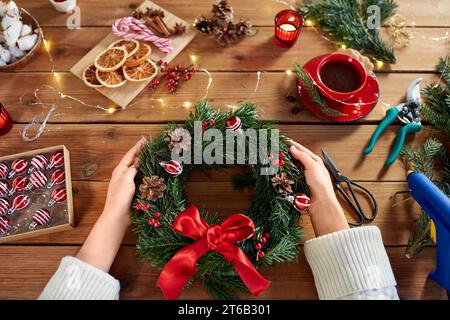 Frau mit handgefertigtem weihnachtskranz zu Hause Stockfoto