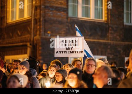 Klang der Stolpersteine Jena eine politisch-künstlerische Aktion Jenaer Bürger, zwar initiiert und koordiniert von Klaus Wegener, Prof. Gerhard Paulus und Till Noack, aber getragen von über 400 Künstlerinnen und Künstlern aus Jena und Umgebung und fast 100 weitere HelferInnen. 9. November, dem Tag der Reichspogromnacht 1938, findet diese in Jena an den Stolpersteinen statt. Ein Besucher hält ein Schild mit der Aufschrift: Keinen Frieden mit Antisemiten hoch bei der Gedenkveranstaltung am Westbahnhof Innenstadt *** Klang der Stolpersteine Jena Eine politisch künstlerische Aktion Jenaer Bürger Stockfoto