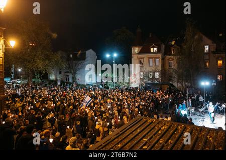 Klang der Stolpersteine Jena eine politisch-künstlerische Aktion Jenaer Bürger, zwar initiiert und koordiniert von Klaus Wegener, Prof. Gerhard Paulus und Till Noack, aber getragen von über 400 Künstlerinnen und Künstlern aus Jena und Umgebung und fast 100 weitere HelferInnen. 9. November, dem Tag der Reichspogromnacht 1938, findet diese in Jena an den Stolpersteinen statt. Hunderte Menschen stehen mit Kerzen vor dem Westbahnhof bei der Gedenkveranstaltung. Israel Flaggen werden getragen Innenstadt *** Klang der Stolpersteine Jena Eine politisch künstlerische Aktion Jenaer Bürger, initiiert Stockfoto