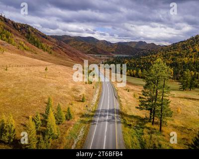 Das Luftbild der Chui Tract Road führt durch die herbstliche Landschaft, die gelben und grünen Hügel und Wälder der Altai Berge in Russland während der Stockfoto