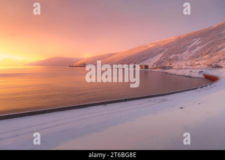 Der wunderschöne Sonnenuntergang über der Bucht Magadan, mit der schneebedeckten Uferpromenade und den Hügeln in der Region Kolyma im russischen Fernen Osten. Stockfoto