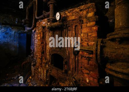 Ein alter rostiger Ofen in einem verlassenen Heizraum. Stockfoto