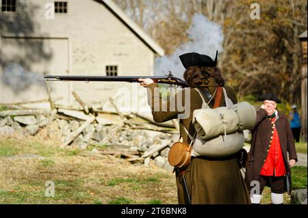 Oktober 2023 Battle Road - Lincoln, Massachusetts. Ein Schauspieler in revolutionärer Kriegsuniform feuert eine Muskete auf dem Feld außerhalb des historischen Hartwell ab Stockfoto