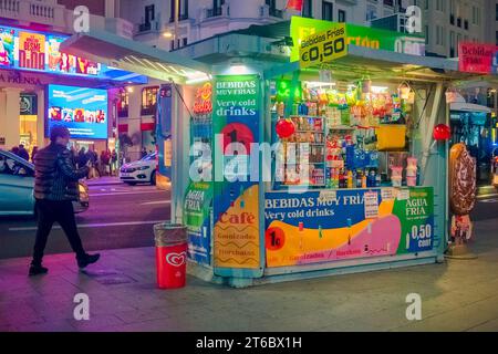 Ein Mann, der in der Nähe eines Kiosks für alkoholfreie Getränke und Süßigkeiten in Callao bei Nacht in Madrid, Spanien, vorbeikommt Stockfoto