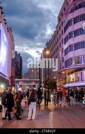 Blick auf die Menschen, die am Abend vor den Ausgängen der Callao Metro laufen, mit dunklen Wolken im Hintergrund, Madrid Spanien. Stockfoto