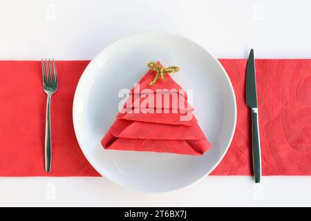 Rote Serviette gefaltet in Kiefernform in Teller mit Besteck-Set.Weihnachten oder Neujahr-Konzept Stockfoto