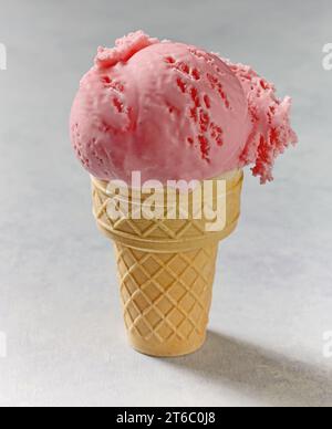 Rosafarbenes Eis in Waffelkegel auf einem Tisch Stockfoto