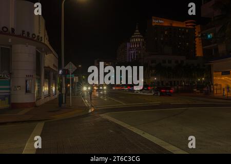 Wunderschöne nächtliche Stadtlandschaft der Miami Beach Street, beleuchtet von Lichtern vorbeifahrender Autos, die lebendiges Licht in die Umgebung werfen. Miami Beach. USA. Stockfoto