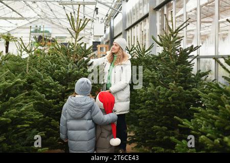 Mutter und Kinder kaufen einen Weihnachtsbaum auf dem Markt. Stockfoto