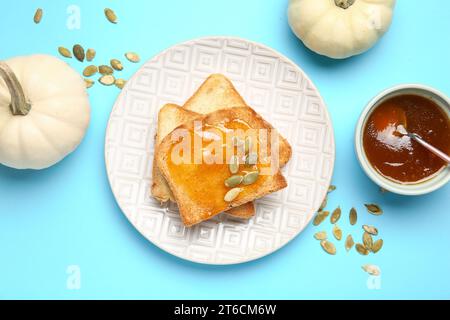 Teller mit süßer Kürbismarmelade und Samen auf blauem Hintergrund Stockfoto