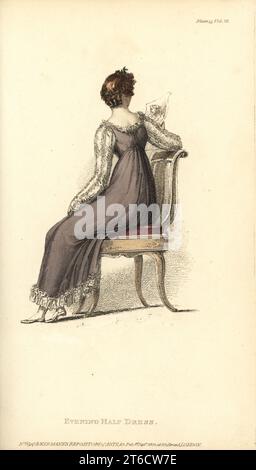 Regency-Frau, die auf einem Stuhl sitzend auf eine Gravur schaut. Abendhalbkleid: Einfarbiges Kleid mit gestreiftem Sarsnet-Netzrücken aus italienischem Netz, blonde Spitzen-Quilling, weiße Satin-Ärmel, Haare in kurzen, vollen Locken hinten. Vol. 12, Platte 15, 1. September 1814. Handkolorierter Kupferstich von Thomas Uwins aus Rudolph Ackermanns Repository of Arts, Strand, London. Stockfoto