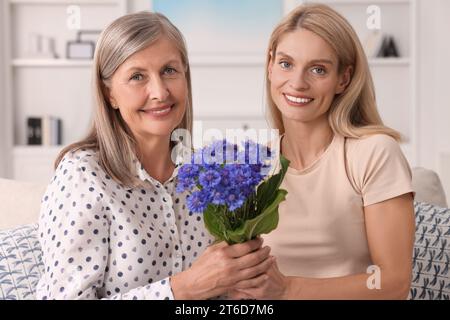 Glückliche reife Mutter und Tochter mit schönen Kornblumen zu Hause Stockfoto