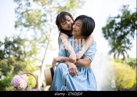 Eine glückliche ältere asiatische Großmutter und ihre süße kleine Enkelin umarmen sich, genießen zarte Momente und kuscheln mit dem Huckepack, während sie Spaß haben Stockfoto