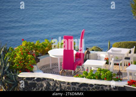 Stilvolle pinkfarbene Stühle auf Santorin mit Blick auf das Mittelmeer Stockfoto