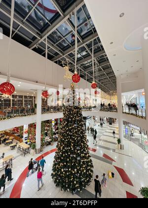 Podgorica, Montenegro - 25. dezember 2022: Hoch dekorierte Weihnachtsbaumstände in der Lobby des Einkaufszentrums Stockfoto