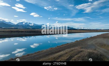 Aus der Vogelperspektive des Pukaki-Wasserkraftkanals im ländlichen Twizel, der parallel zum heute bedeckten Ben Ohau-Gebirge verläuft Stockfoto