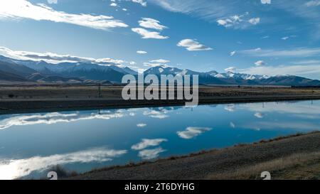 Aus der Vogelperspektive des Pukaki-Wasserkraftkanals im ländlichen Twizel, der parallel zum heute bedeckten Ben Ohau-Gebirge verläuft Stockfoto