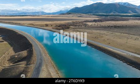 Aus der Vogelperspektive des Pukaki-Wasserkraftkanals im ländlichen Twizel, der parallel zum heute bedeckten Ben Ohau-Gebirge verläuft Stockfoto