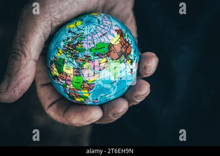 Nahaufnahme von oben eines anonymen Mannes, der kleine Erdkugel in zerknitterten Händen zeigt Stockfoto