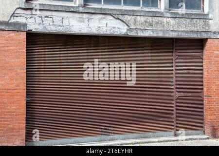 Alte geschlossene rostige Metallrollläden am Fassadeneingang, altes Gebäude Stockfoto
