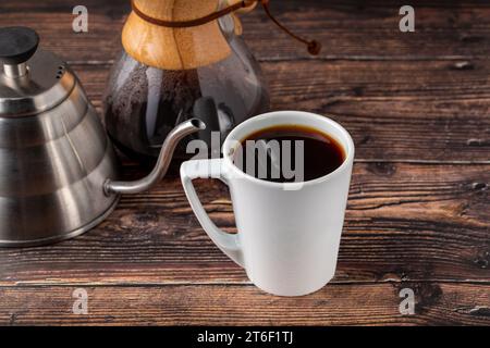 Eine Tasse Kaffee und die dritte Generation gießen über die Kaffeemaschine auf dem Steinboden Stockfoto