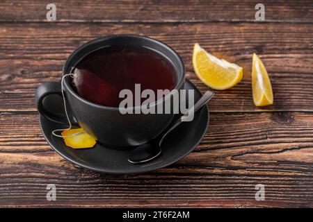 Abgepackter, gebrühter Wintertee in schwarzem Porzellanbecher auf Holztisch Stockfoto