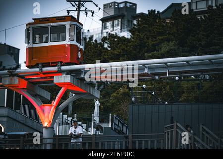 Eine rot-weiße Seilbahn befindet sich auf einer Strecke, mit einem leuchtend gelben Pfeil nach vorne Stockfoto