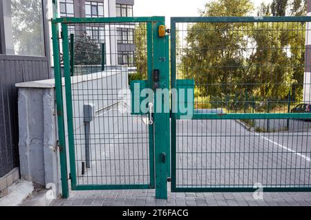 Eingangstür zum Innenhof. Metalldrahtzaun. Grüne Eingangstüren aus Metall. Die Fernbedienung zum Öffnen der Heckklappe durch Motorautomatisierung ist zu Hause Stockfoto