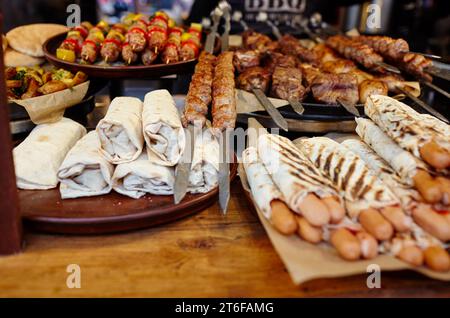 Weihnachtliches Street Food Festival auf Messe im Stadtzentrum, Winterferien. BBQ Street Food zum Verkauf, leckere Würstchen auf dem Holiday Street Market in europa Stockfoto