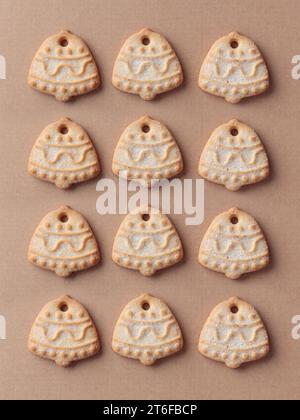 Frisch gebackene hausgemachte glockenförmige zuckerweihnachtskekse auf dem Kunsthandwerk-Hintergrund, vertikal Stockfoto
