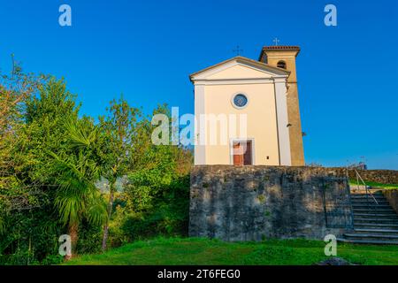 Wunderschöne kleine Kirche aus dem Mittelalter gegen blauen klaren Himmel und Bäume an einem sonnigen Tag in Castello, Malcantone, Tessin, Schweiz Stockfoto