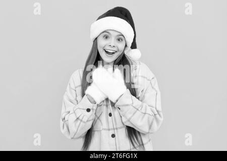 Wintermode. Frohes neues Jahr. frohe weihnachten. Ein glücklicher Junge mit santa claus Hut. teenager in Handschuhen auf gelbem Hintergrund mit Kopierraum. weihnachtsfeiertage. Stockfoto