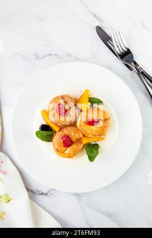 Muffins mit Pfirsich, Himbeere, schwarzer Beere und Minze mit Puderzucker, Seitenansicht Stockfoto