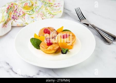 Muffins mit Pfirsich, Himbeere, schwarzer Beere und Minze mit Puderzucker, Seitenansicht Stockfoto