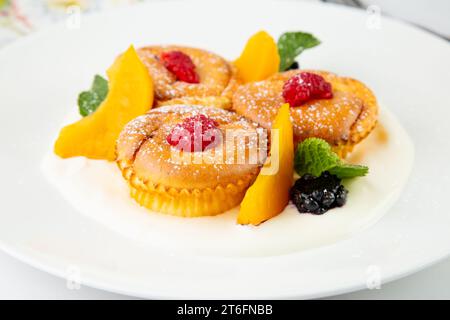 Muffins mit Pfirsich, Himbeere, schwarzer Beere und Minze mit Puderzucker, Seitenansicht Stockfoto