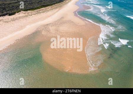 Aus der Vogelperspektive ziehen sanfte Wellen über eine Sandbar am Strand von Inverloch in Gippsland, Victoria, Australien. Stockfoto