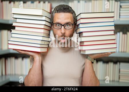 Lehrertag. Guter Lehrer. Tutor im Klassenzimmer. Mann Lehrer mit Büchern im Klassenzimmer. Wissens- und Bildungskonzept. Lustiger Lehrer hält viele Bücher Stockfoto