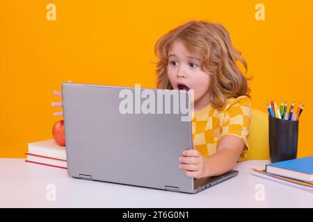 Erregtes Schulkind mit Laptop-Computer. Schulkinder lernen im Unterricht, lernen englisch in der Schule. Grundschulkind Stockfoto