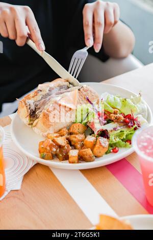 Eine Person, die Roastbeef mit offenem Gesicht Sandwich mit Gemüse auf der Seite hat. Stockfoto