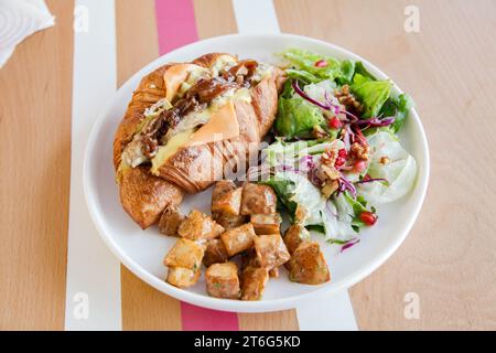 Offenes Sandwich mit offenem Hähnchencroissant und Gemüse an der Seite. Stockfoto