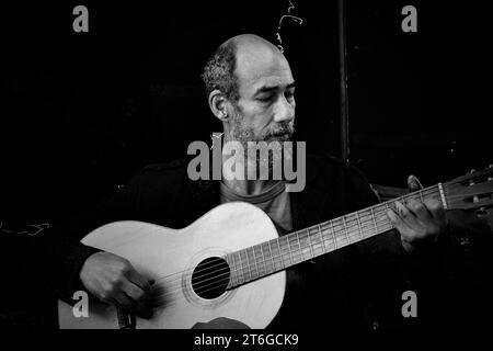 Ein Straßenkünstler spielt die Gitarre, die er von einem anderen Obdachlosen für £5 gekauft hat. Er nutzt es für busk und ergänzt sein Einkommen Stockfoto