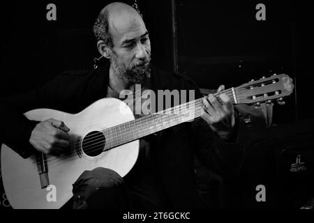 Ein Straßenkünstler spielt die Gitarre, die er von einem anderen Obdachlosen für £5 gekauft hat. Er nutzt es für busk und ergänzt sein Einkommen Stockfoto