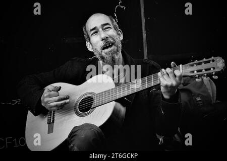 Ein Straßenkünstler spielt die Gitarre, die er von einem anderen Obdachlosen für £5 gekauft hat. Er nutzt es für busk und ergänzt sein Einkommen Stockfoto