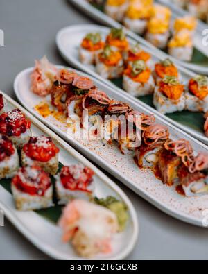 japanisches Sushi. Maki und Brötchen mit Thunfisch, Lachs, Garnelen, Krabben und Avocado. Rainbow Sushi Roll, Uramaki, Hosomaki und Nigiri. Stockfoto