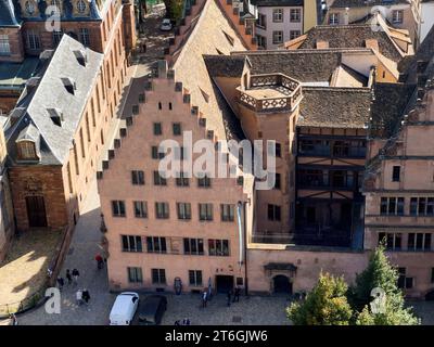 Blick aus der Vogelperspektive: Museumswerk Notre-Dame, ein historisches Gebäude mit Silhouettenfiguren darunter und entfernten Wohngebäuden - ein fesselnder Blick auf Straßburgs Sehenswürdigkeiten Stockfoto