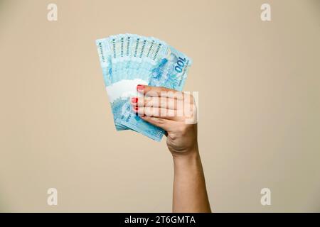 Mehrere hundert echte Rechnungen - Geld aus Brasilien in einer Frauenhand mit roten Nägeln - Rückseite Stockfoto