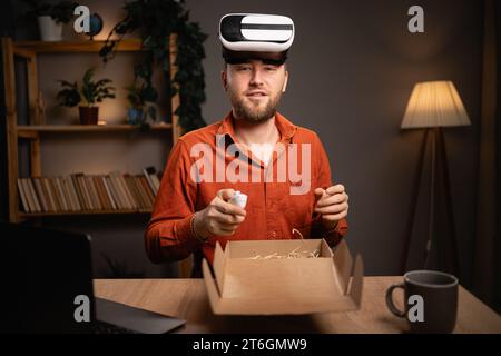 VR-Helm. Gutaussehender Mann als professioneller Videoblogger, der Unboxing-Videos erstellt Stockfoto