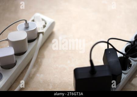 Überlastete Stromversorgungsplatinen. Steckdosenleisten mit verschiedenen Steckern auf weißem Boden. Konzept der Gefahr Gefahr Überlaststrom elektrisch Stockfoto